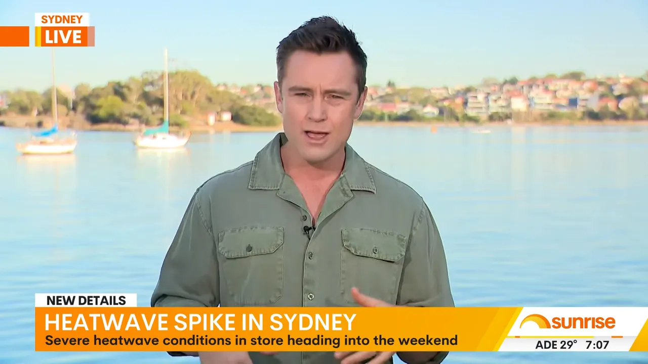 Sunrise TV presenter reporting from the Bay Run waterfront with boats and shoreline behind him