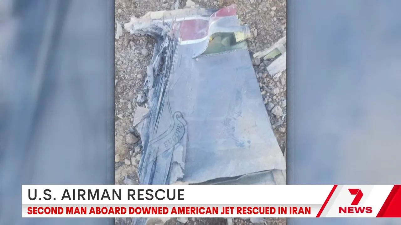 Close view of a damaged aircraft wreckage at the crash site, with news banner about an American jet rescued in Iran