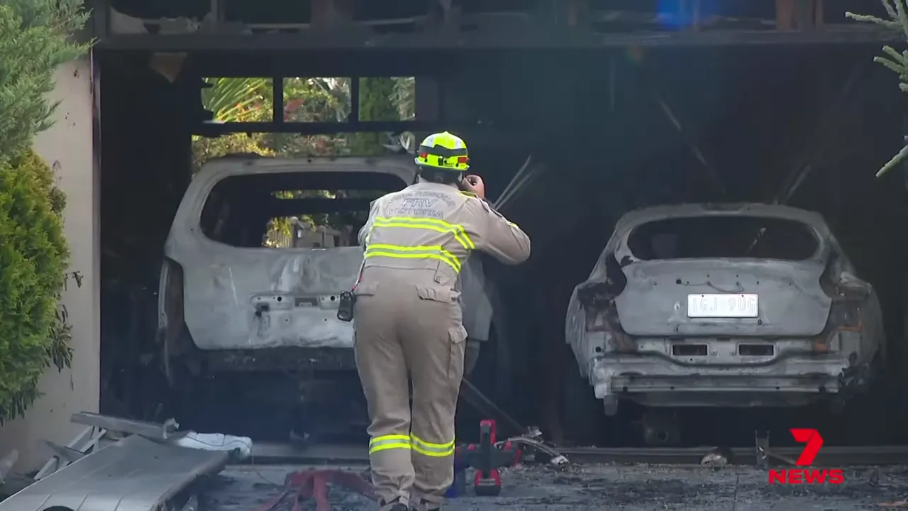 Fire investigator photographing two burnt cars inside a charred garage
