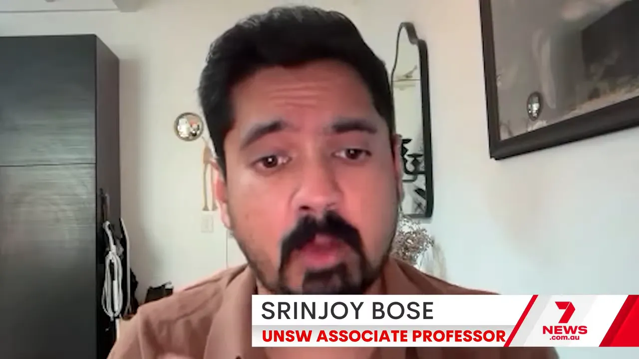 Video-call screenshot of an academic labelled as an associate professor giving expert commentary.