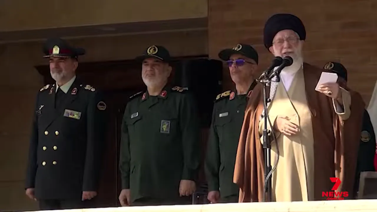 Wide shot of a cleric at a microphone with three senior military officers standing beside him on a platform