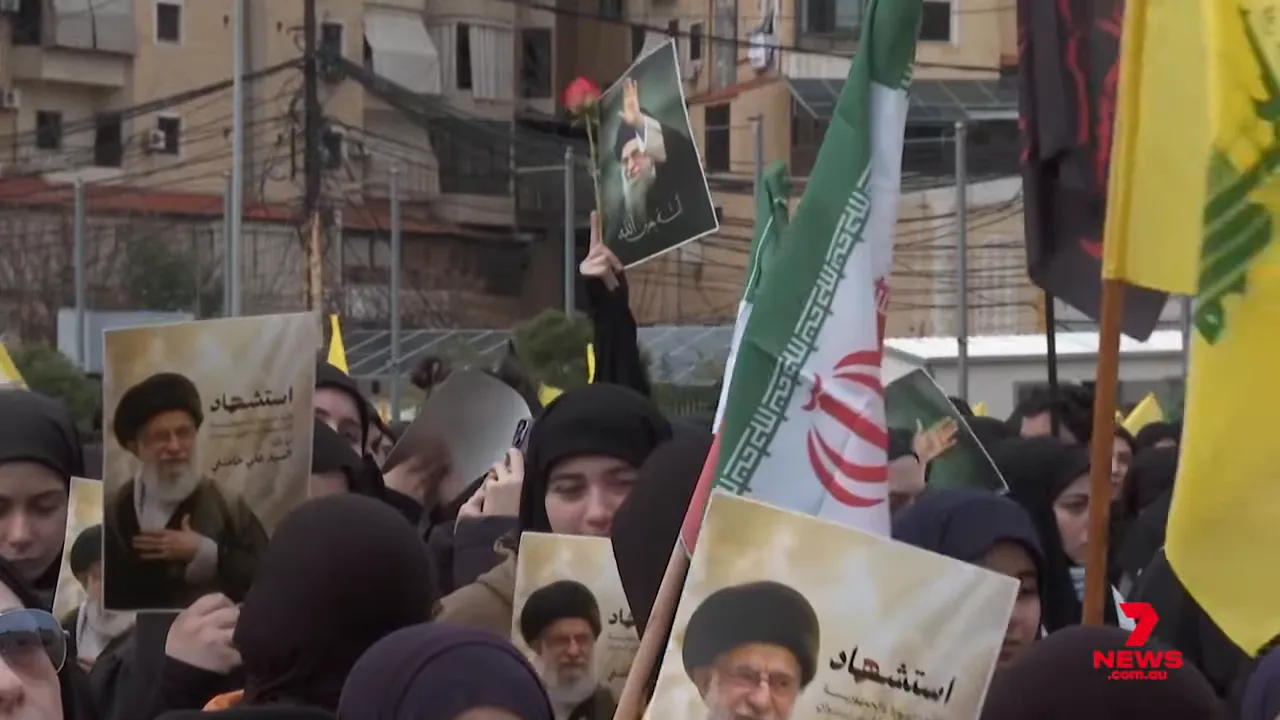 Crowd of supporters holding portraits of Ali Khamenei and Iranian flags at a rally