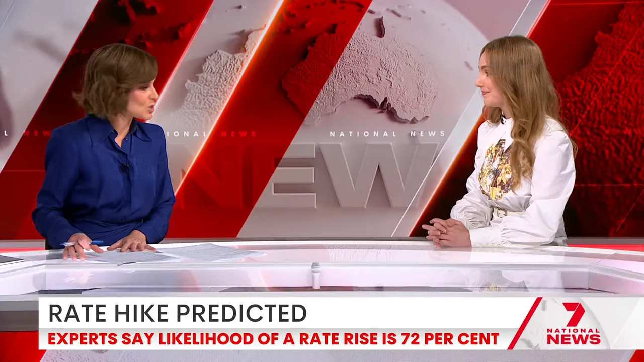 Two news presenters seated across a desk in the studio discussing a predicted rate hike, with chyron 'Rate hike predicted'