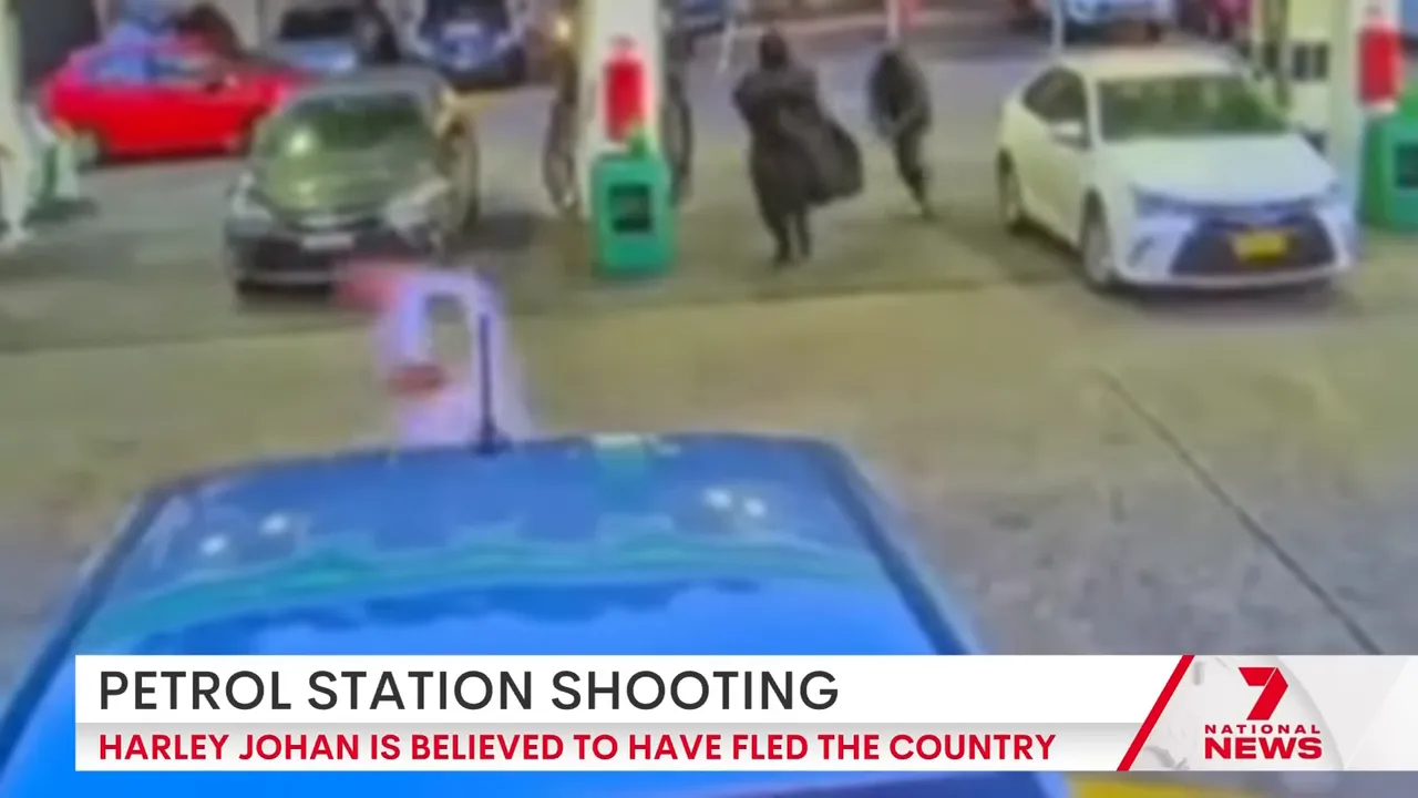 Two masked figures at the petrol station; one appears to wear a poncho