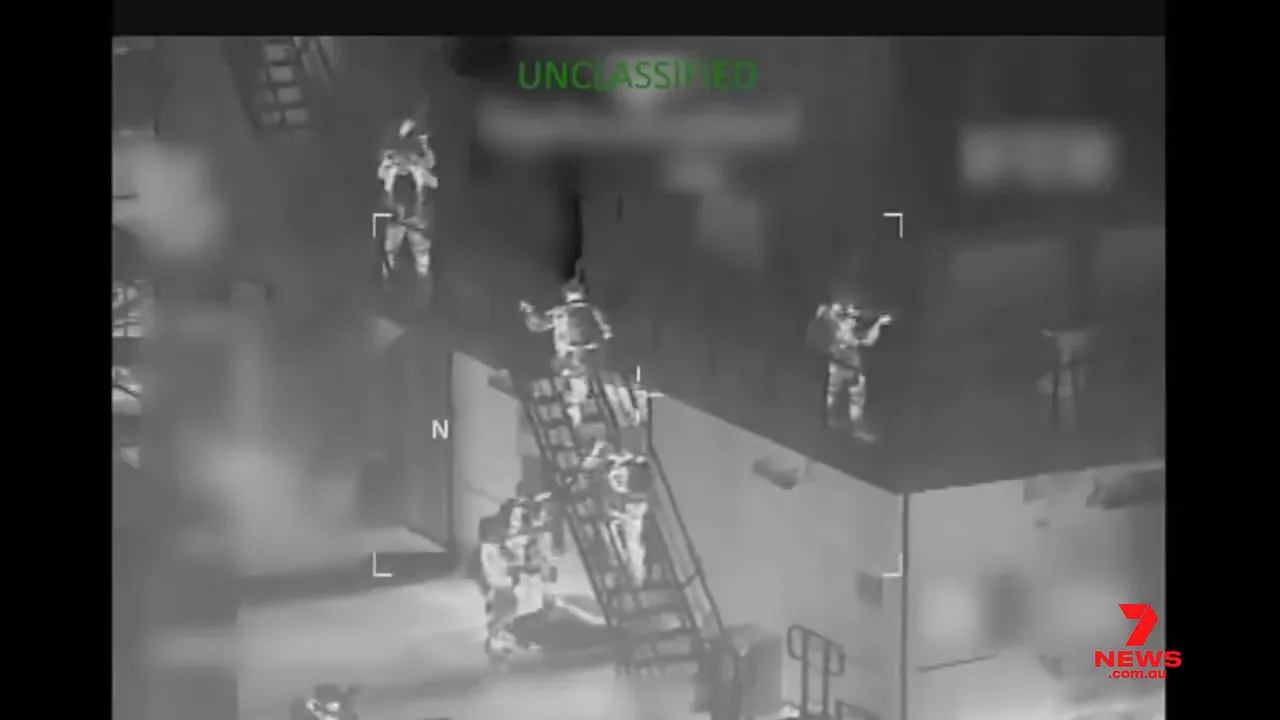Sharp thermal aerial image showing multiple boarding team members climbing a ladder and moving on the tanker’s deck; 'UNCLASSIFIED' text visible at top and 7NEWS watermark at bottom right.