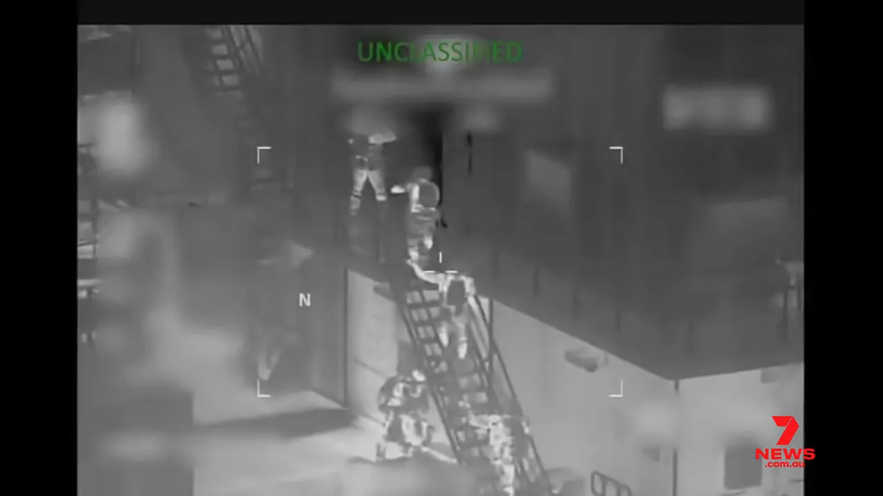 thermal image showing a boarding ladder and multiple crew members climbing onto the tanker during an interdiction