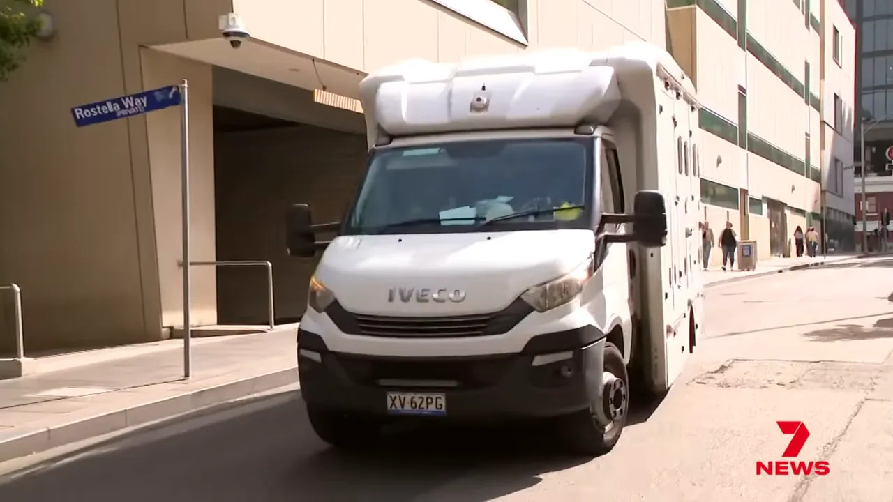 Front view of a white Iveco prisoner transport van driving past the court, 7 News logo