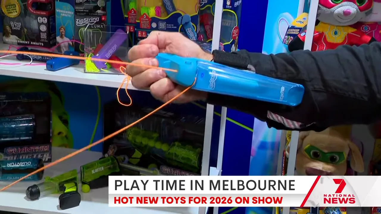 Close-up of a blue ZipString Arcana arm‑strapped web‑shooter being held and extended, with the orange filament visible.