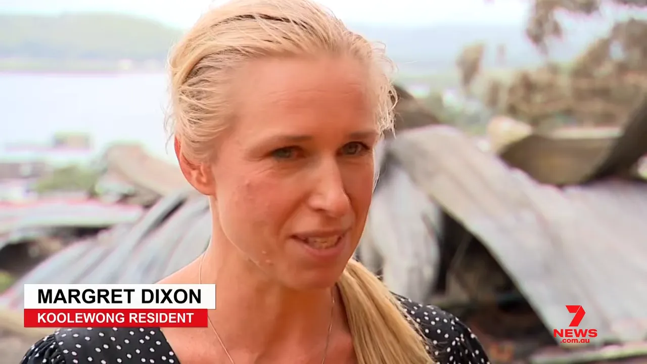 Resident standing in front of charred corrugated iron debris after the Koolewong bushfire