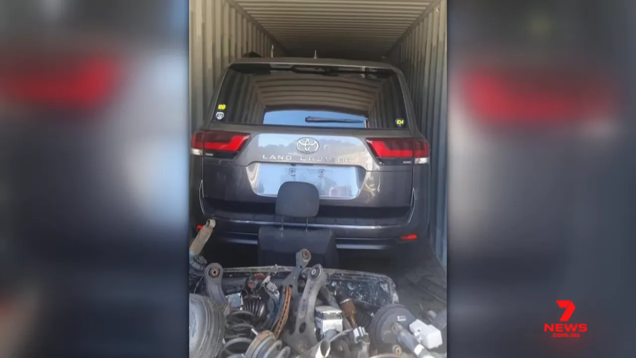 Rear of a Toyota Land Cruiser parked inside a shipping container with automotive parts piled in front