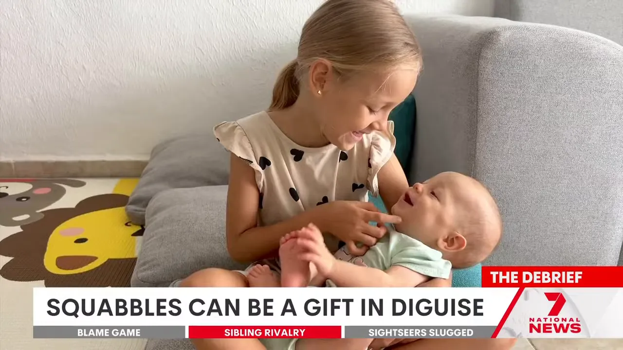 Older girl smiling and gently playing with a baby sibling on a couch