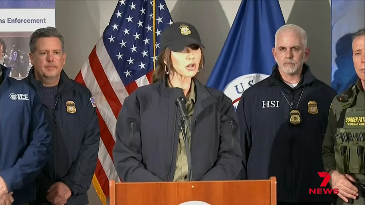 Wide view of a federal press conference: speaker at a podium flanked by multiple federal officials, the US flag and agency insignia visible.