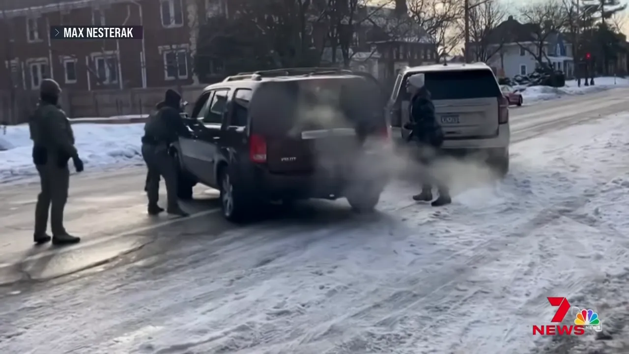 Close shot of agents at the side and rear of a dark SUV with another person standing by on a snowy street