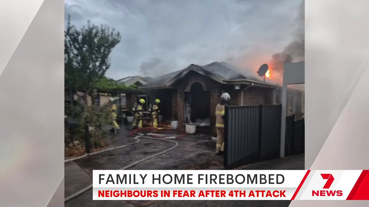 Firefighters working outside the charred entrance of a suburban house with hoses and smoke