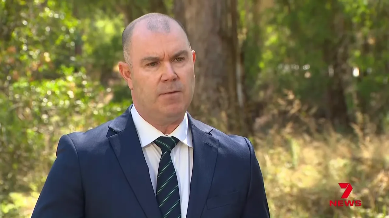 Senior police officer speaking outdoors near trees and long grass about investigation scenarios