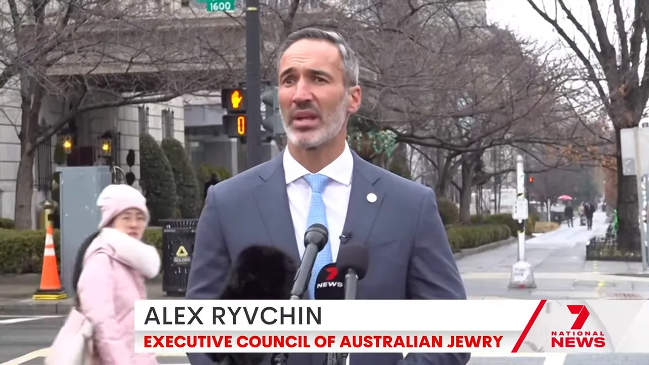 Community leader speaking into multiple microphones at an outdoor press podium on a city street.