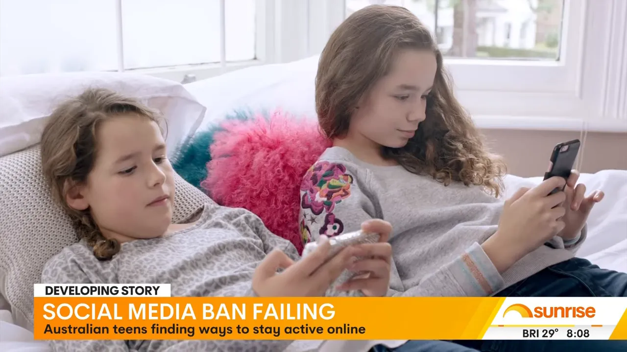 two teenage girls lying on a bed each using a smartphone