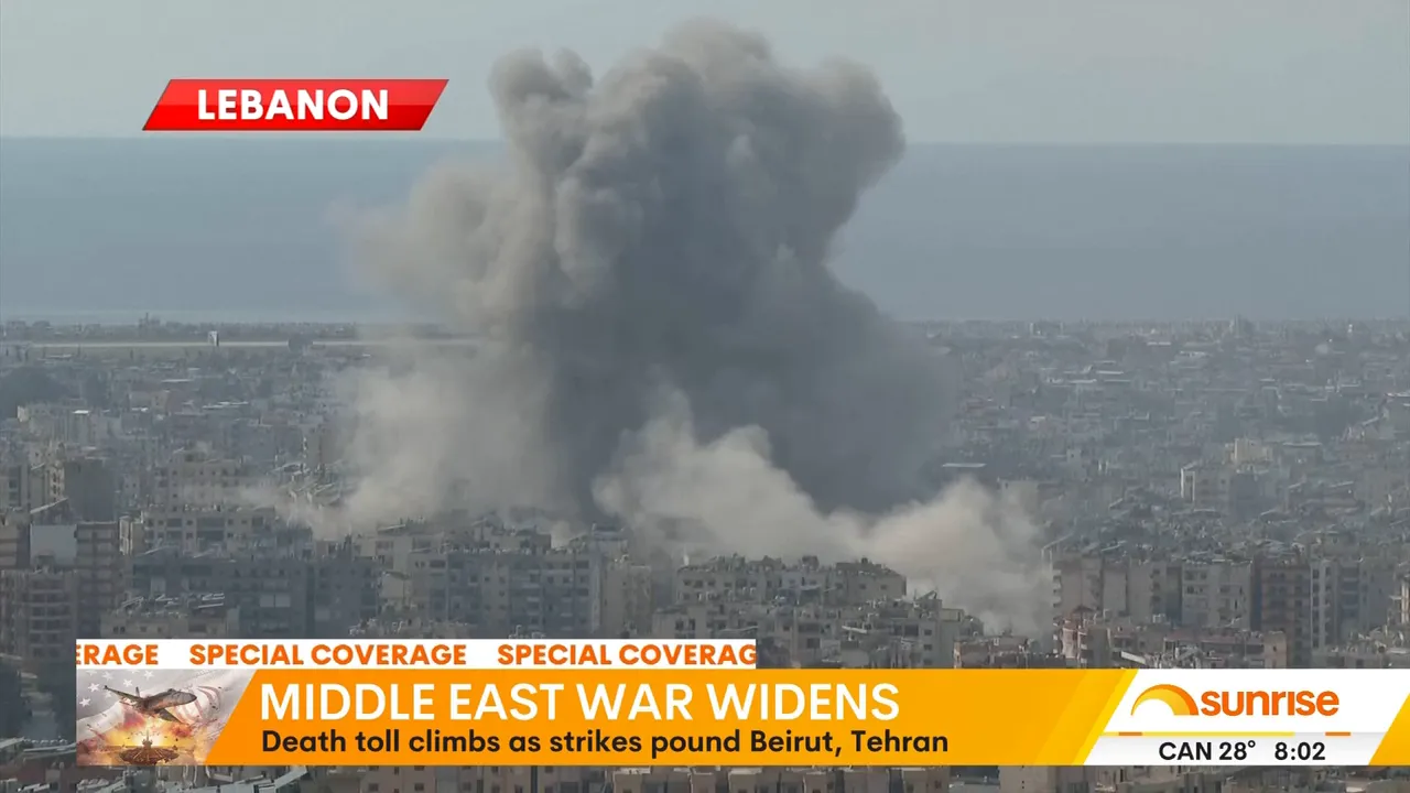 Aerial view of a large grey smoke cloud rising above a coastal city after an explosion or strike