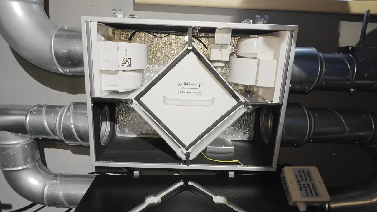 Geöffnetes Lüftungsgerät mit rautenförmigem Plattenwärmetauscher, zwei Ventilatoren und angeschlossenen Luftleitungen