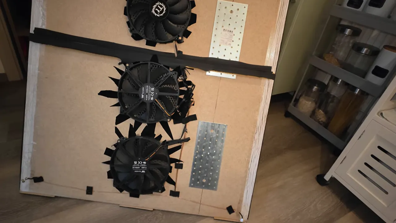 Rückseite einer abgenommenen Holzverkleidung mit drei Ventilatoren und elektrischen Verbindungen