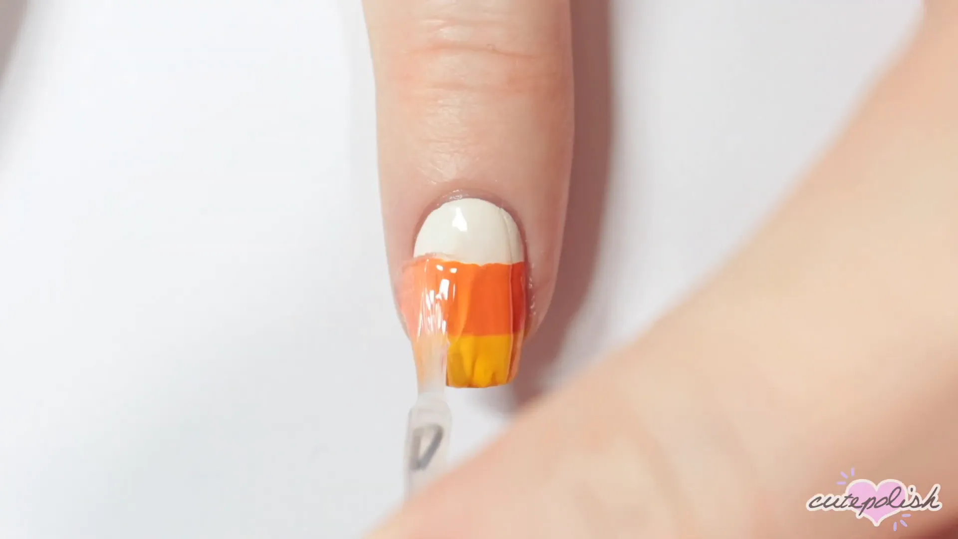 Spooktacular Nail Art: 10 Easy Halloween Designs 8 Completing the candy corn design with a top coat.