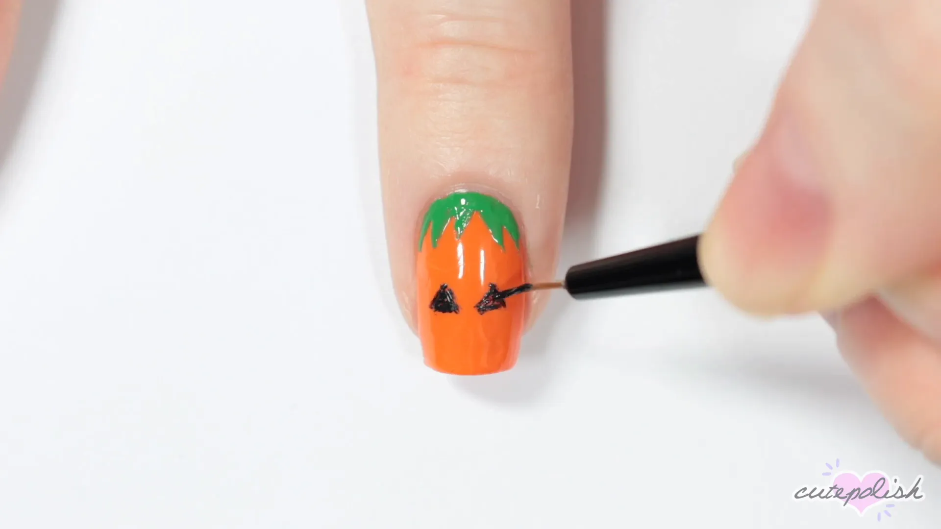 Spooktacular Nail Art: 10 Easy Halloween Designs 5 Painting the Jack-o'-Lantern face with eyes and mouth.