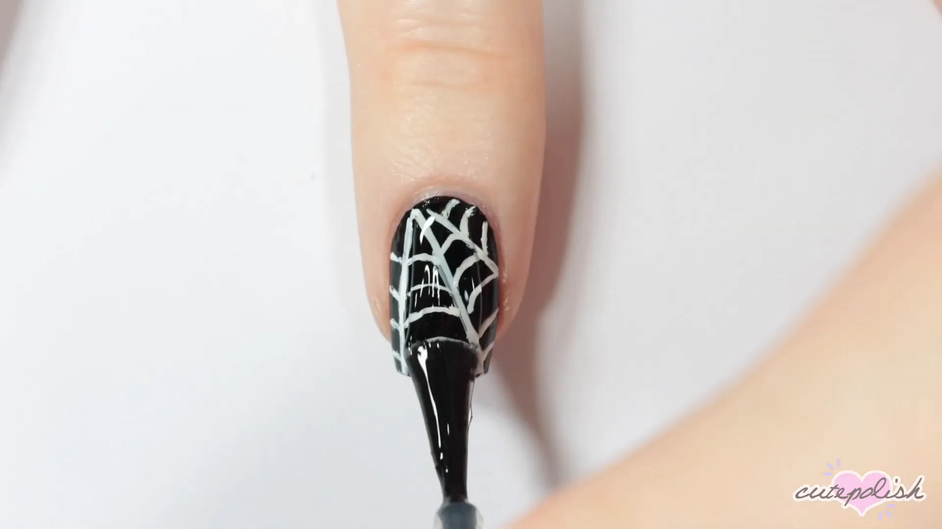 Spooktacular Nail Art: 10 Easy Halloween Designs 18 Completing the spiderweb design with a top coat.