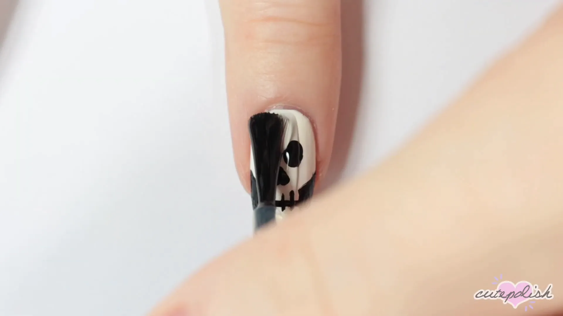 Spooktacular Nail Art: 10 Easy Halloween Designs 20 Adding details to the skull design.