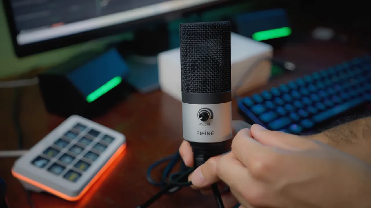 Main réglant la molette de gain sur la face avant du microphone FIFINE K669S