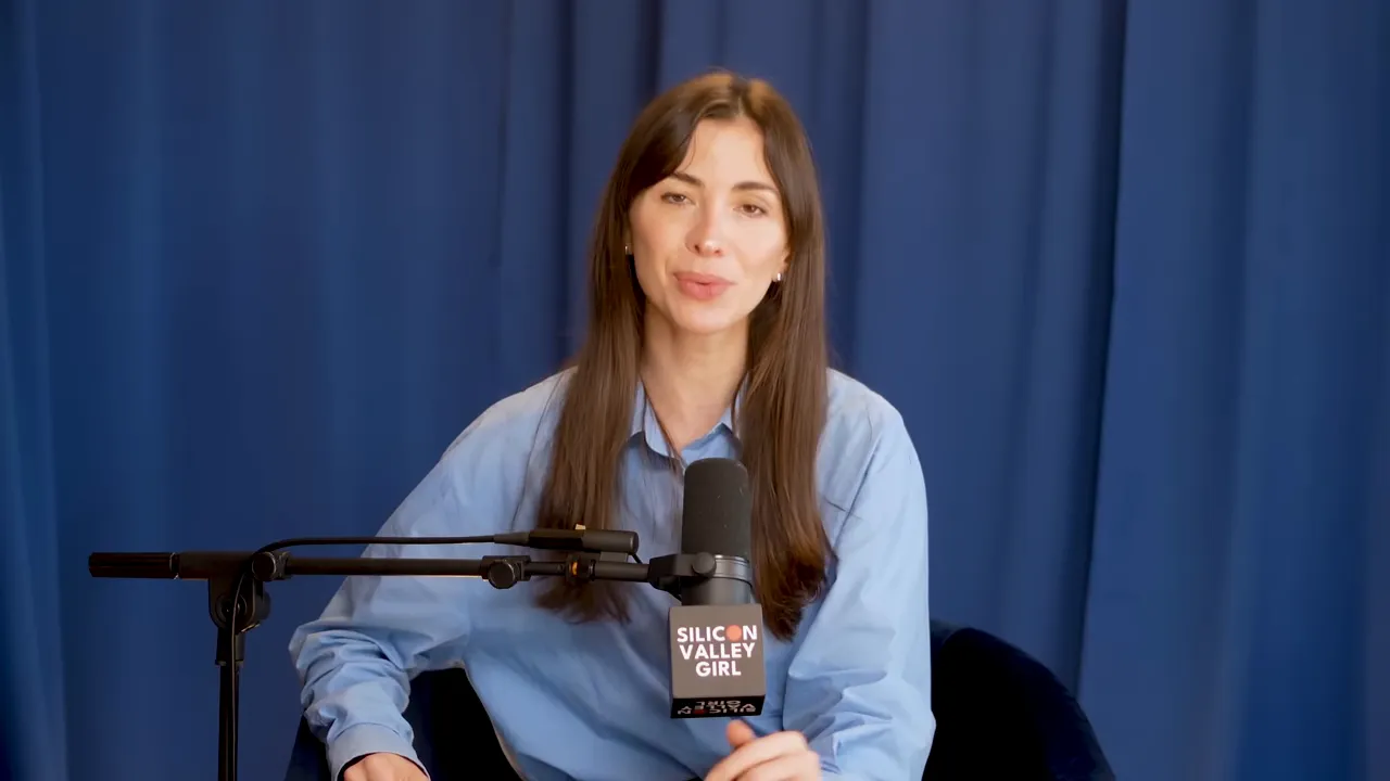Podcast host speaking into a microphone against a blue curtain, addressing the audience.