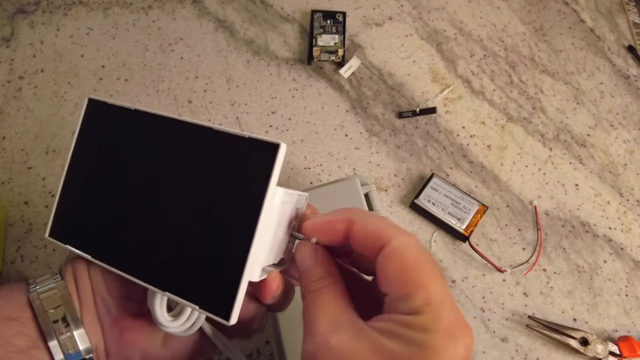 Close-up of solar panel being secured to its bracket with a small screw while battery and board sit nearby