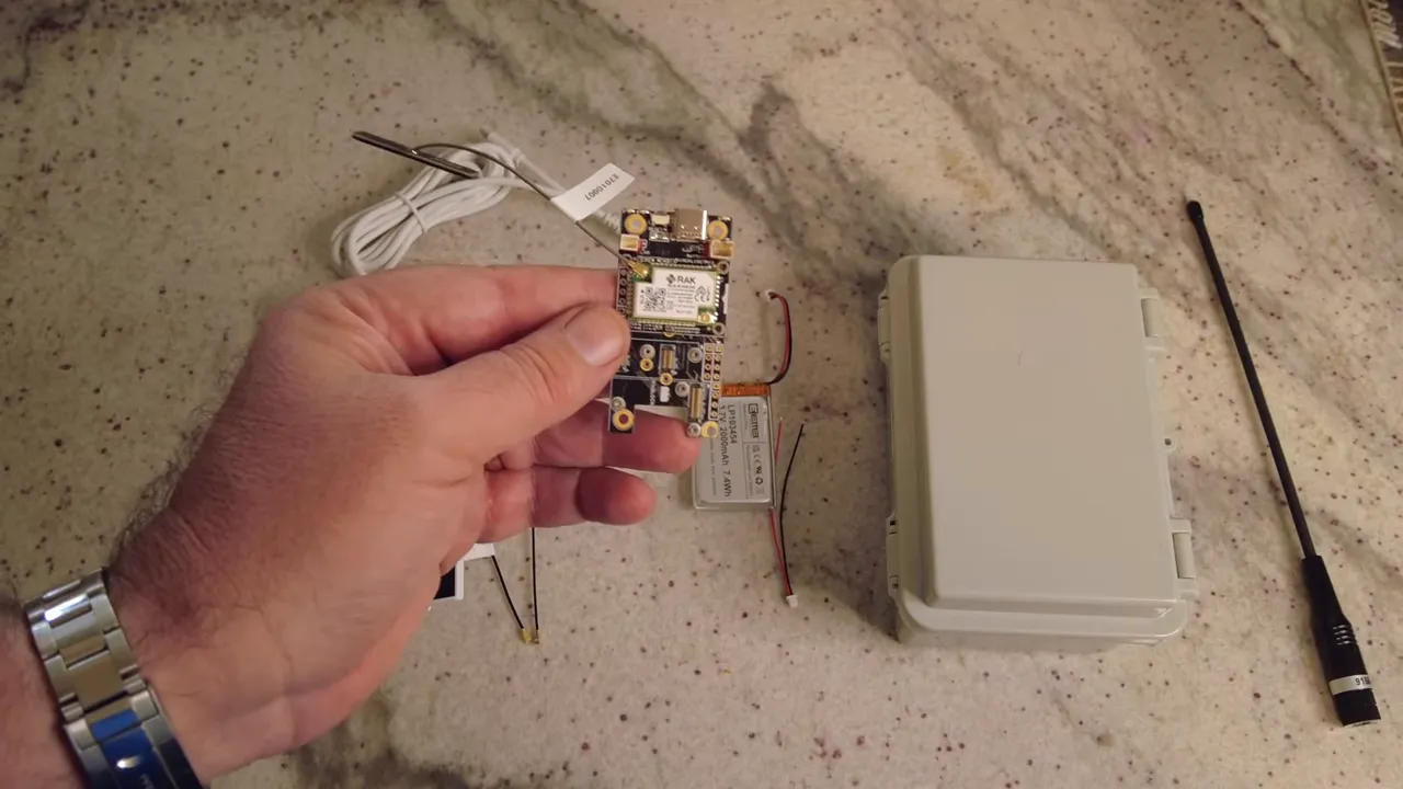 RAK Wireless wisblock board, 18650 battery, small solar panel, antenna and waterproof enclosure on a work surface