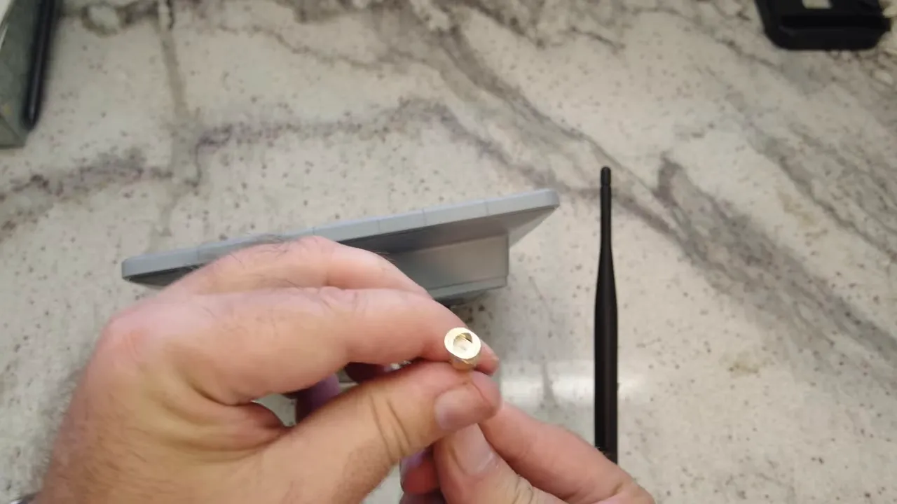 Close-up of SMA-to-Type N adapter showing the inner pin with the SenseCAP and antenna in the background