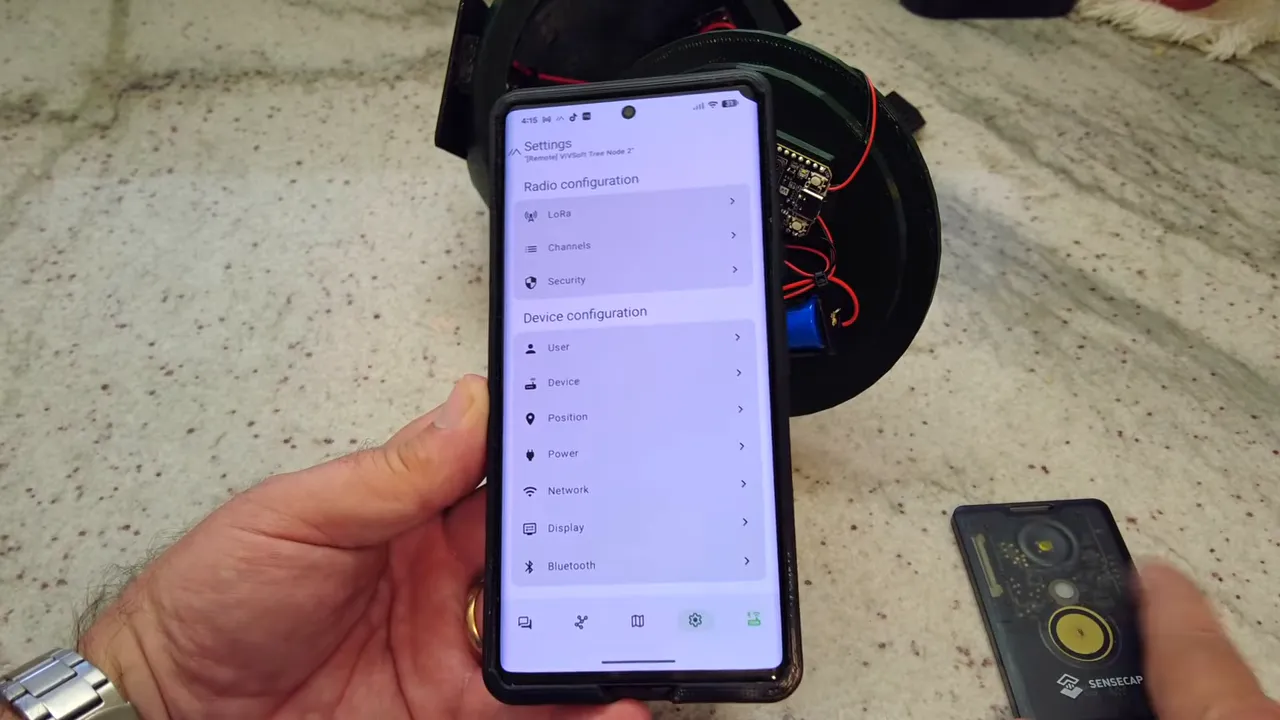 Smartphone showing Meshtastic settings with SenseCAP hardware setup in view