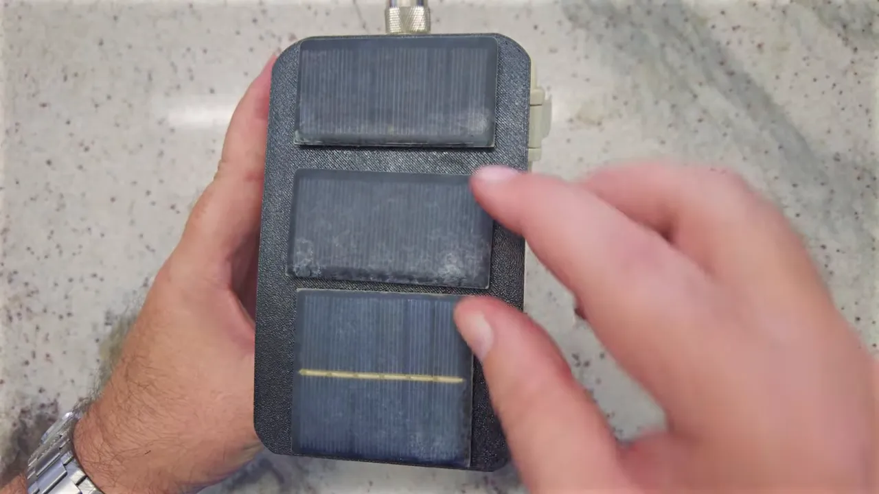 close-up clear view of three small solar cells mounted on a node enclosure with a finger pointing