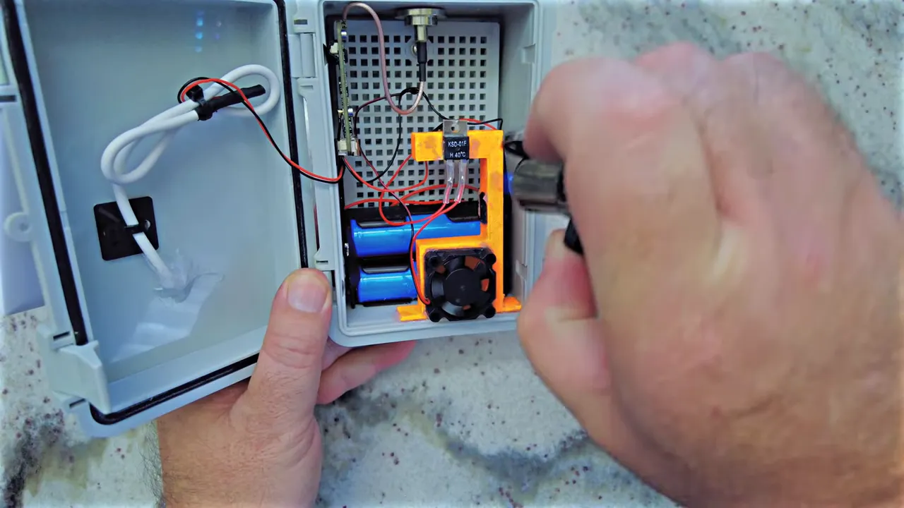 close-up of KSD-01F thermal switch mounted on orange 3D-printed duct next to small fan and 18650 batteries