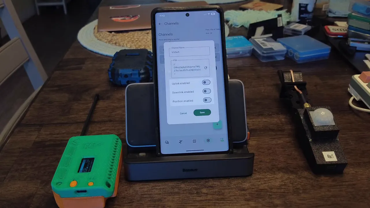 Smartphone on a stand displaying the Meshtastic Channels dialog with channel name 'VIVSoft' and a long PSK key visible.