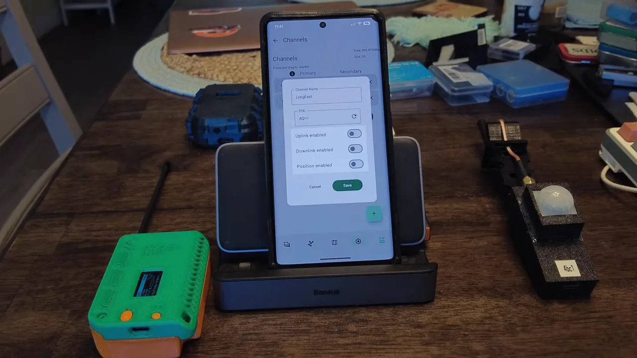 Centered phone screen with Meshtastic Channels dialog open showing Channel Name 'LongFast' and PSK 'AQ==' (no hand obstructing view)