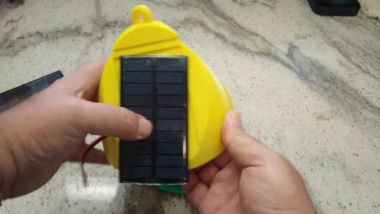 Small solar panel pressed onto the yellow 3D-printed node body showing the wire and top hook.