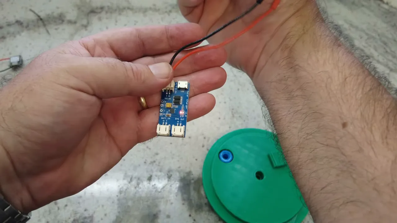 Charge controller with red charging LED illuminated and red/black solar wires connected, ready for installation.