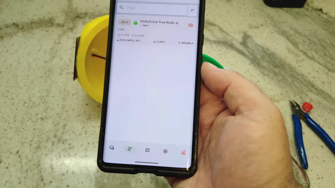 Close-up of the Meshtastic app listing 'ViVSoft.live Tree Node' with an online indicator and battery icon visible on the phone screen.