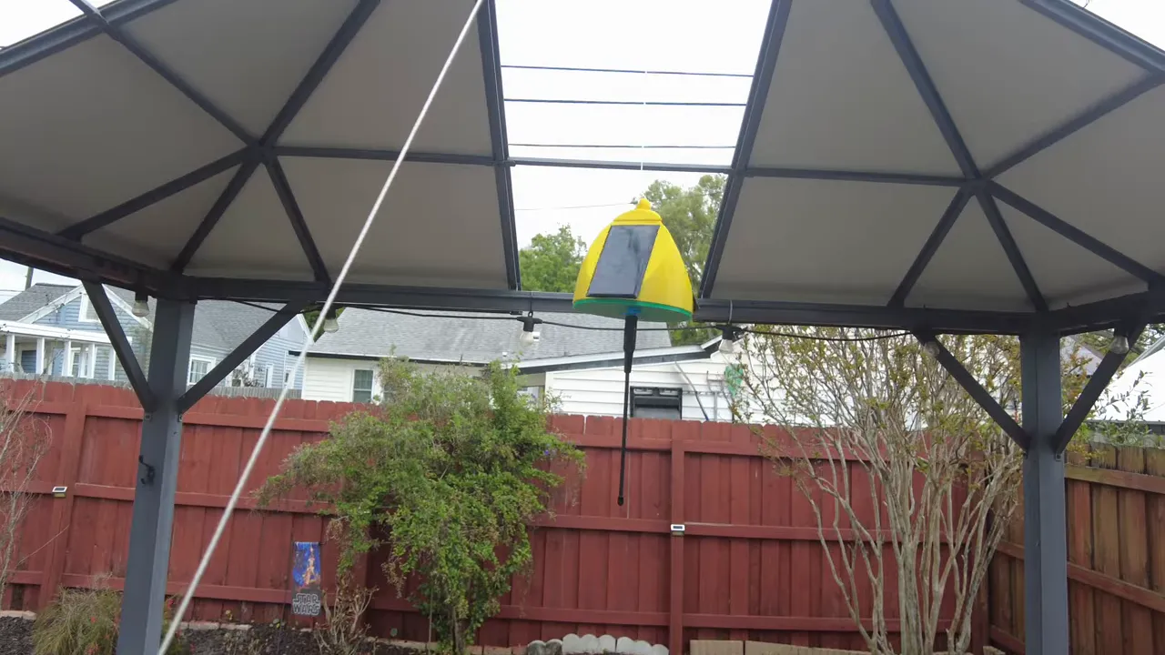 Close view of Meshtastic solar tree node hanging under gazebo, visible solar panel and whip antenna