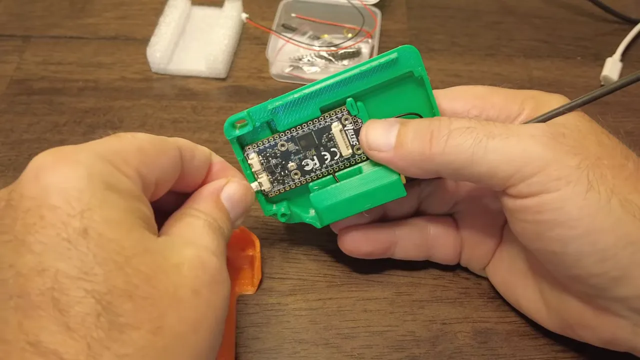 Clear overhead shot of Heltec V4 board inside a green case with connectors visible and hands holding it