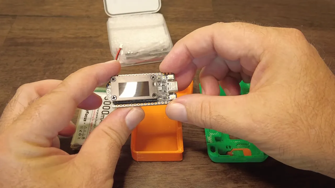 Heltec V4 board held in hands with visible display, USB connector and header pins