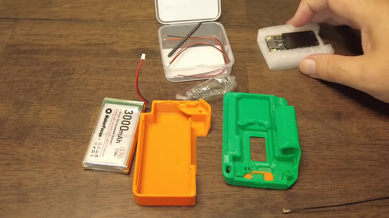 3000mAh battery, antenna cable, Heltec board and 3D-printed case pieces on a table