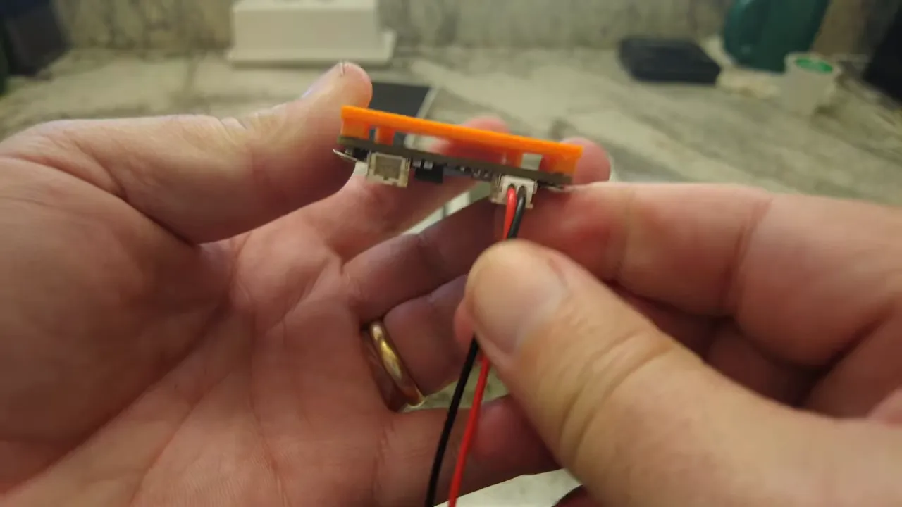 Close view of red and black power wires inserted into the SolarXaio board's JST connector, clearly showing polarity.