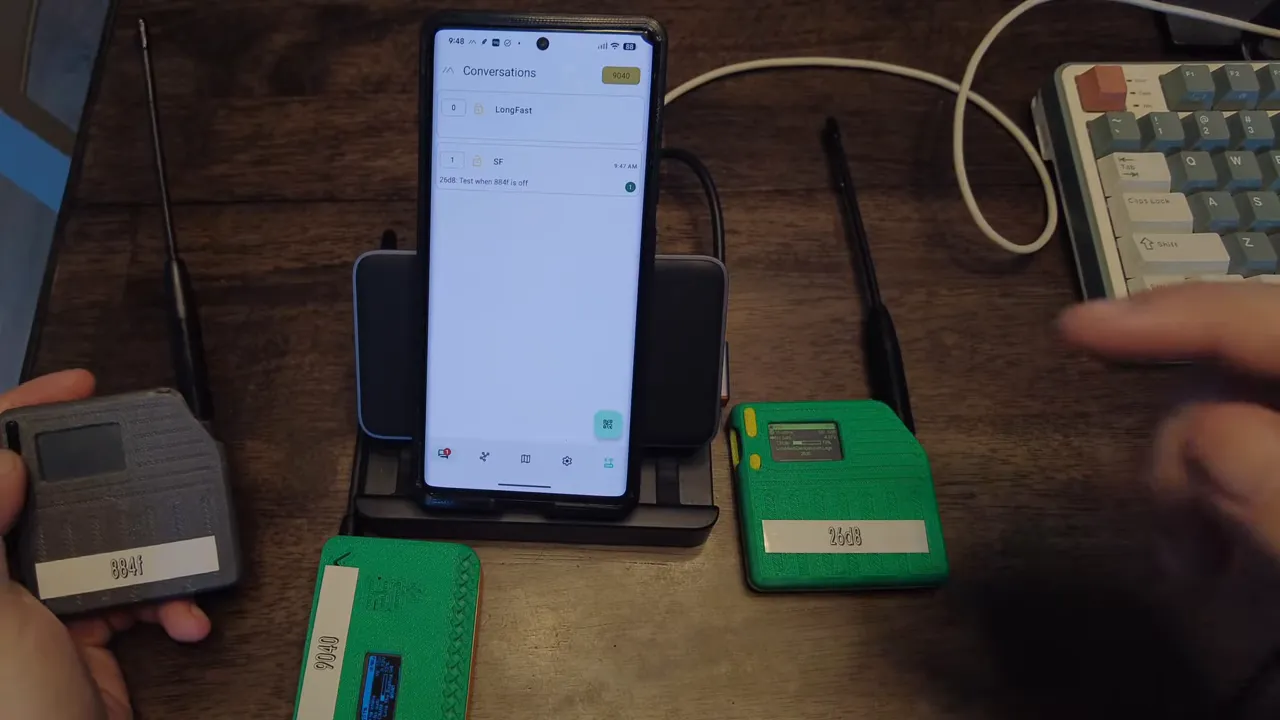 Centered phone running Meshtastic showing the Conversations list (LongFast and SF) with three LoRa nodes arranged around it on a desk.
