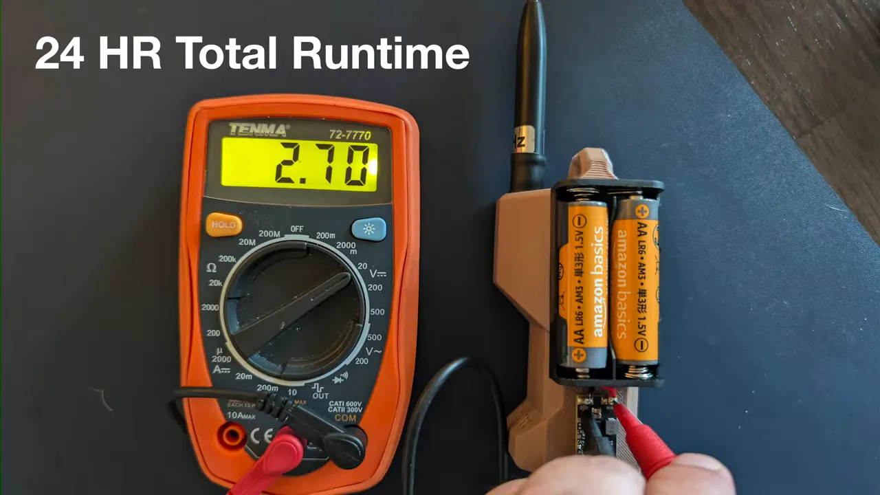 Digital multimeter showing 2.70 volts beside the AA battery pack and antenna with text indicating 24 hour total runtime