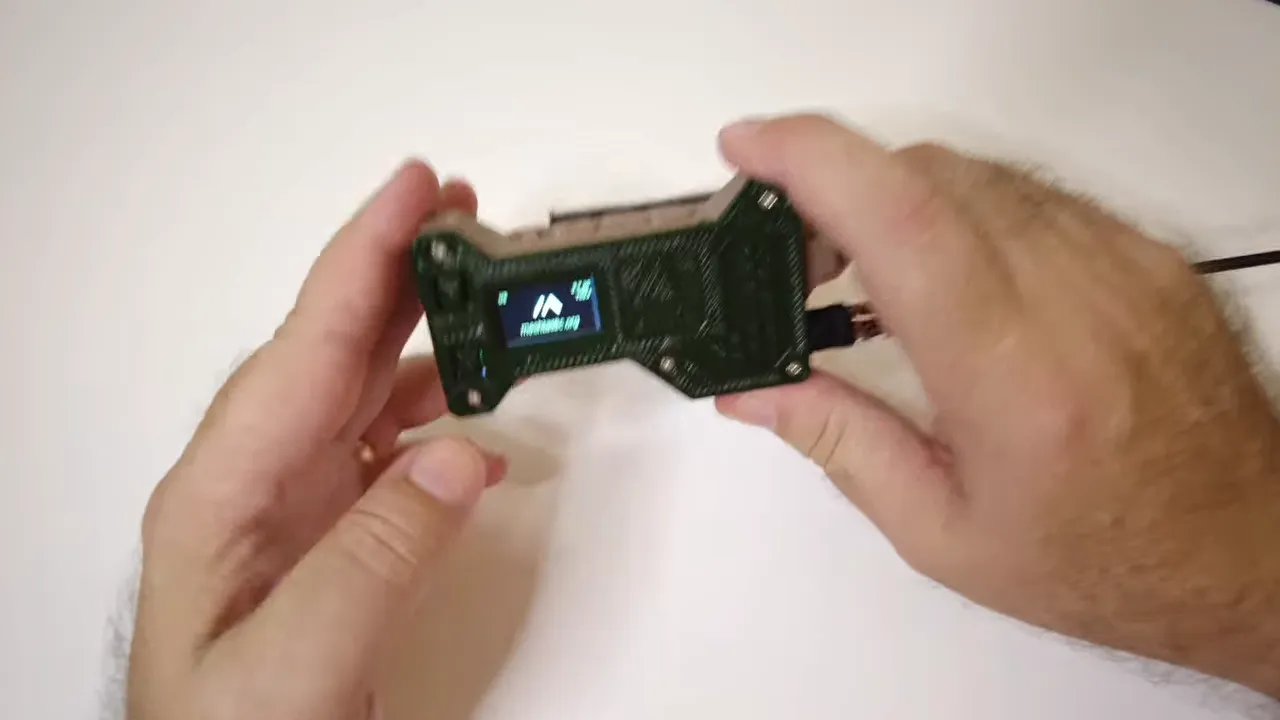 Heltec T096 powered on with the screen lit while the modified case is held in both hands