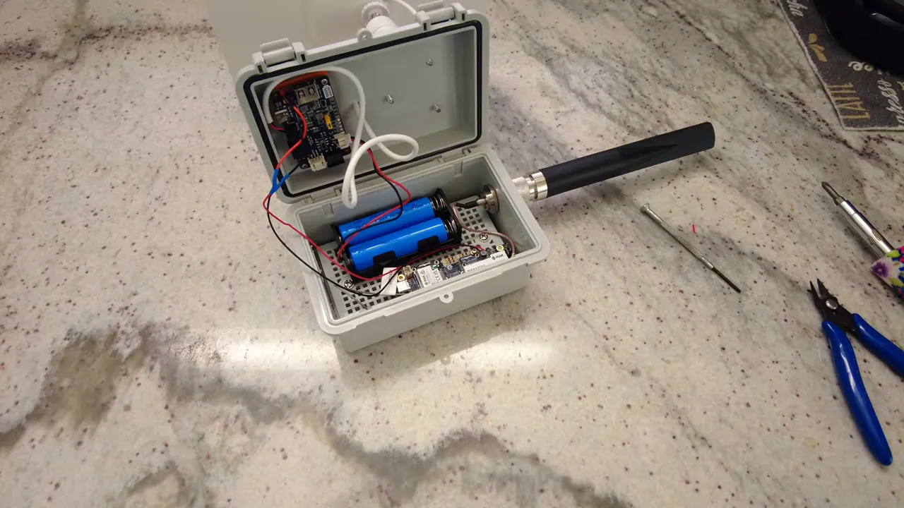 Open waterproof enclosure with 18650 battery pack, solar charge board, RAK 1W module, antenna connected and solar cable routed.